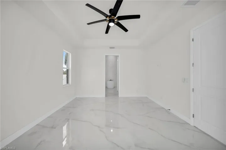 Unfurnished room featuring visible vents, a ceiling fan, a tray ceiling, and baseboards