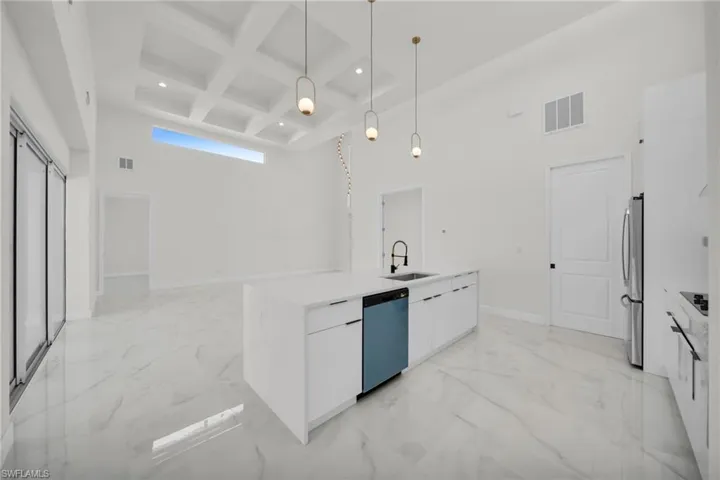 Kitchen featuring a sink, modern cabinets, a towering ceiling, dishwasher, and freestanding refrigerator