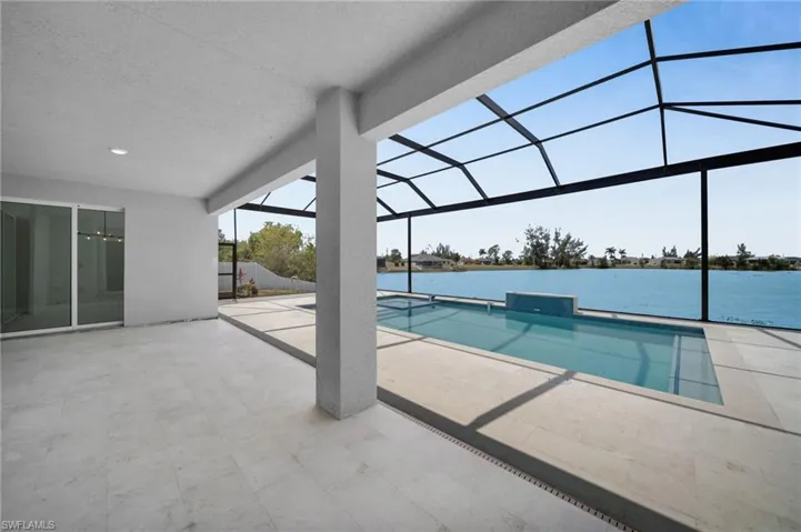 Pool featuring glass enclosure, a water view, and a patio area