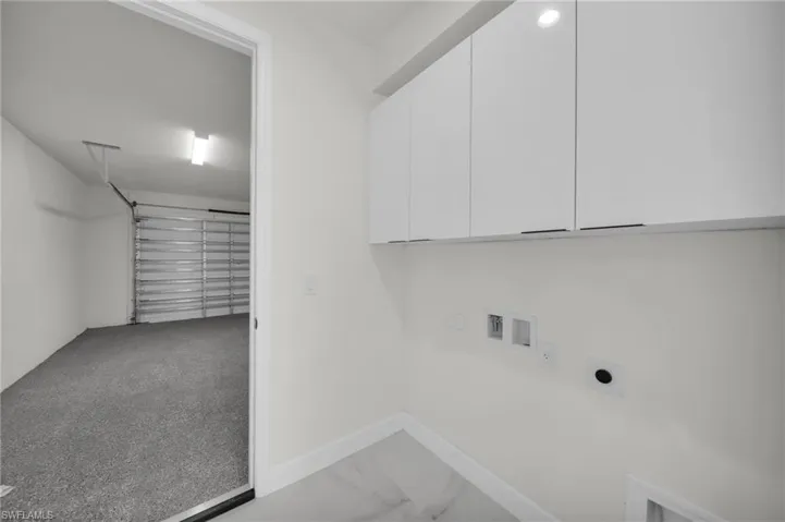 Washroom with hookup for a washing machine, cabinet space, hookup for an electric dryer, hookup for a gas dryer, and baseboards