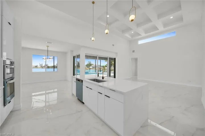 Kitchen with a sink, stainless steel appliances, a towering ceiling, modern cabinets, and marble finish floor