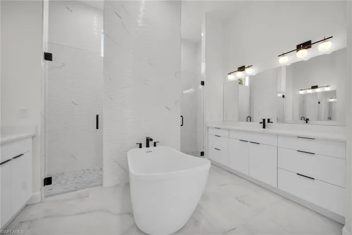 Full bath featuring a freestanding tub, a marble finish shower, vanity, and marble finish floor