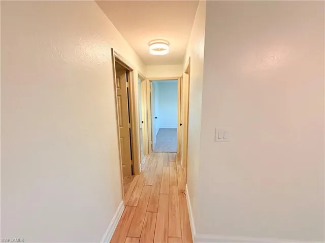 Corridor featuring baseboards and light wood-style floors