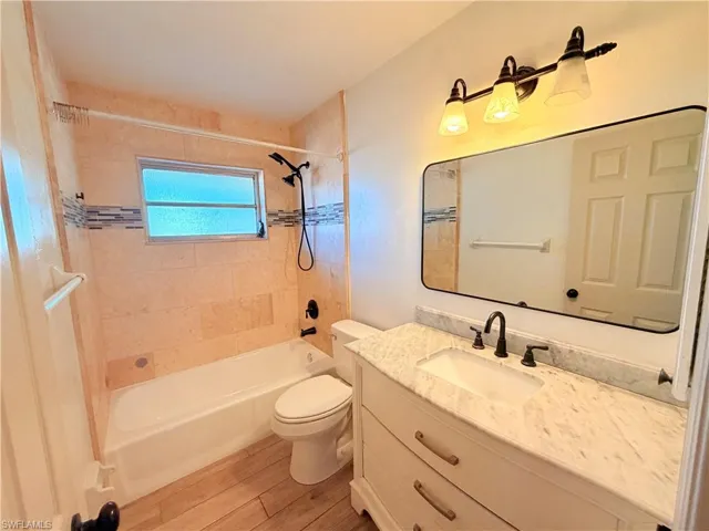 Bathroom featuring vanity, bathtub / shower combination, and light wood-style floors