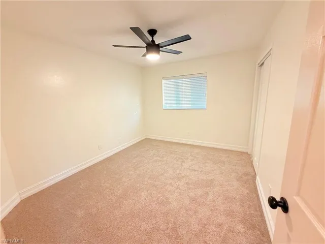 Unfurnished bedroom featuring light colored carpet, a ceiling fan, and a closet