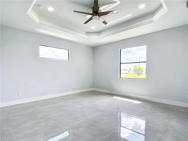 Spare room with tile floors, ceiling fan, and a raised ceiling