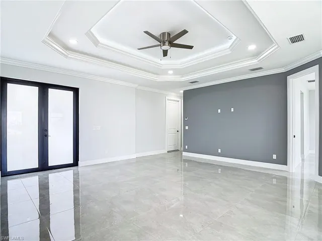 Tiled spare room with a tray ceiling, ceiling fan, french doors, and ornamental molding