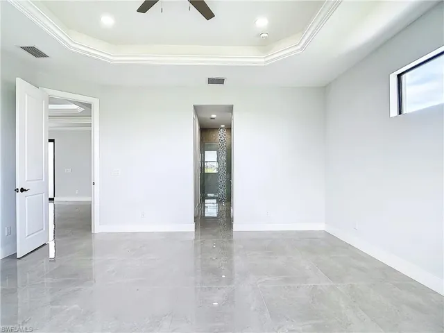 Tiled spare room featuring ceiling fan, a tray ceiling, and crown molding