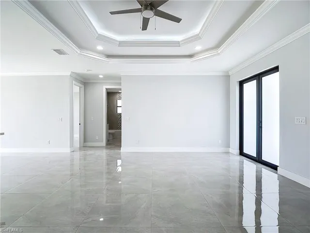 Unfurnished room with plenty of natural light, ceiling fan, a tray ceiling, and crown molding