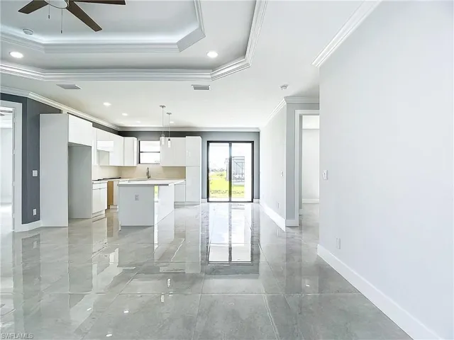Kitchen with crown molding, white cabinetry, a kitchen island, a tray ceiling, and ceiling fan