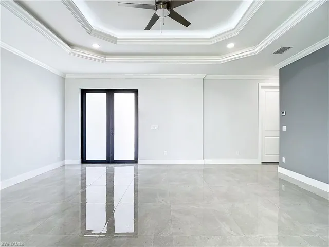 Tiled spare room featuring ceiling fan, a raised ceiling, and crown molding