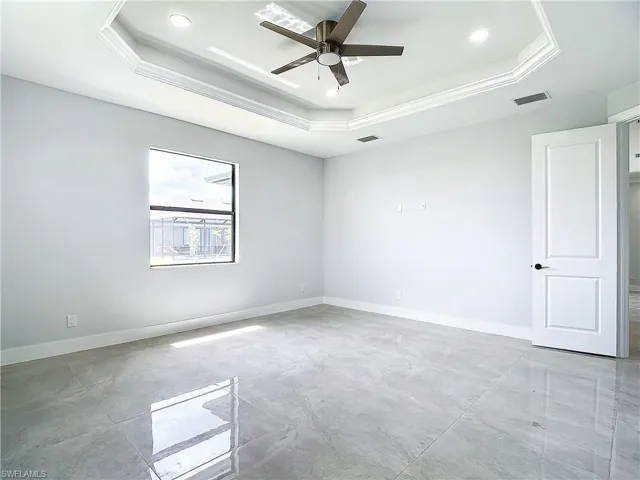 Tiled spare room with ceiling fan and a raised ceiling