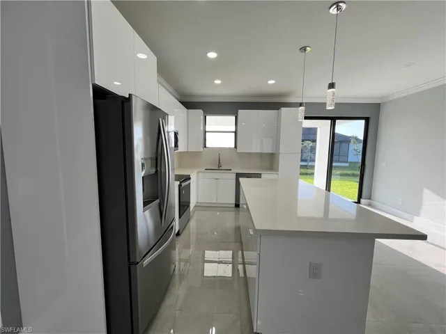 Kitchen with stainless steel appliances, white cabinets, sink, pendant lighting, and light tile patterned floors