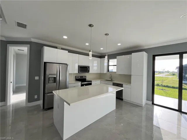 Kitchen with white cabinetry, stainless steel appliances, light tile patterned floors, and a kitchen island
