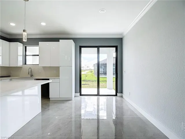 Kitchen featuring tasteful backsplash, light tile flooring, pendant lighting, sink, and white cabinetry