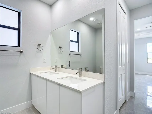 Bathroom with tile floors, toilet, and double sink vanity