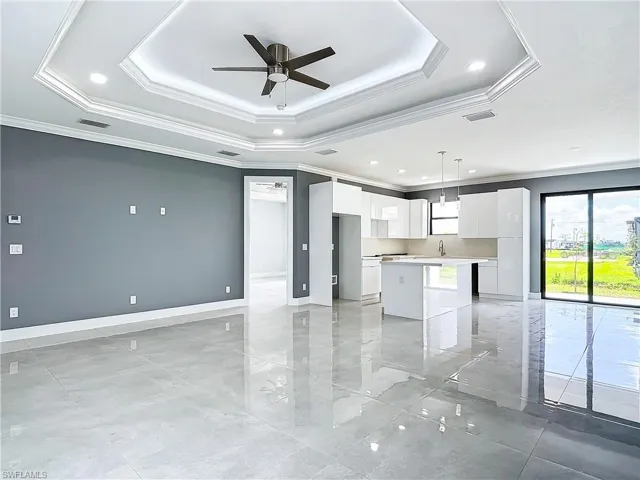 Unfurnished living room featuring a tray ceiling and light tile floors