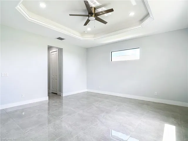 Tiled spare room with ceiling fan and a tray ceiling