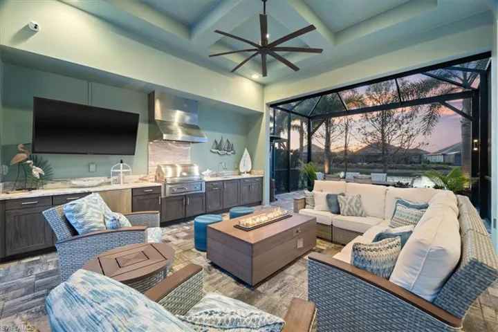 View of patio with an outdoor kitchen, a lanai, area for grilling, a ceiling fan, and an outdoor living space with a fire pit