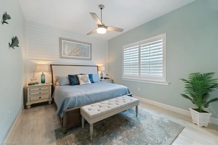 Bedroom with an accent wall, ceiling fan, baseboards, and wood finished floors