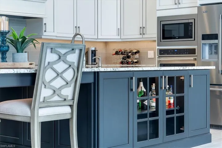 Kitchen featuring appliances with stainless steel finishes, blue cabinetry, glass insert cabinets, and decorative backsplash