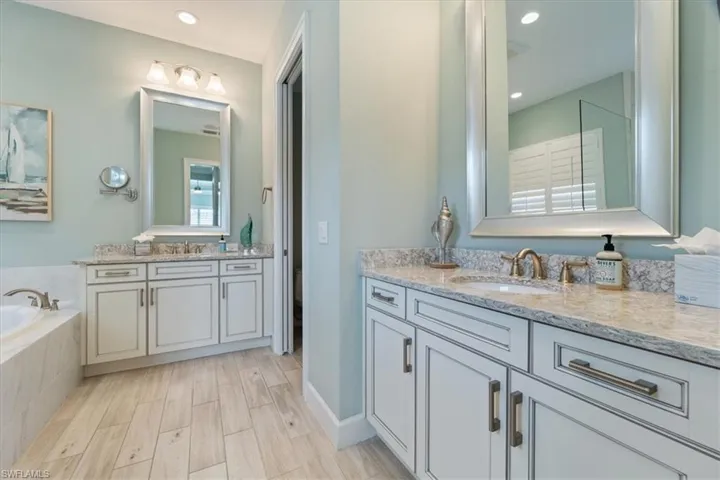 Full bathroom with a bath, two vanities, a sink, and wood finished floors