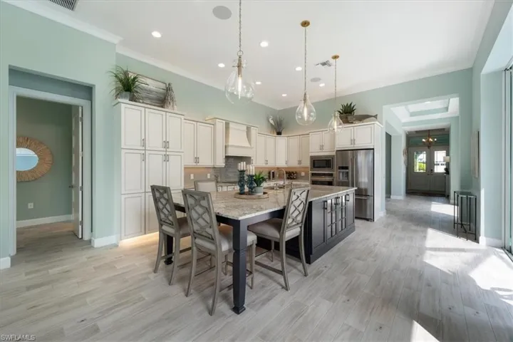 Kitchen featuring premium range hood, appliances with stainless steel finishes, ornamental molding, light wood-type flooring, and backsplash