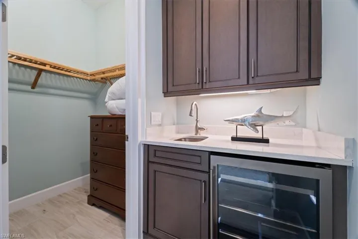 Bar with wine cooler, a sink, and baseboards