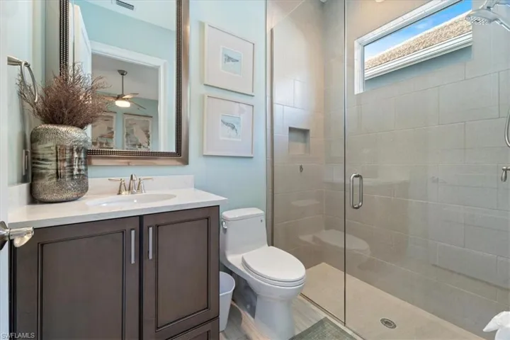 Bathroom with toilet, visible vents, a stall shower, and vanity