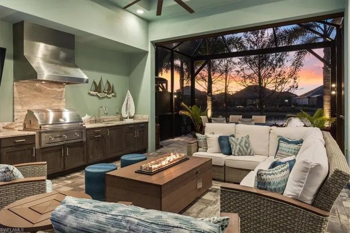 View of patio / terrace with a sink, glass enclosure, area for grilling, and an outdoor living space with a fire pit