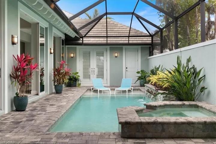 View of swimming pool with glass enclosure, a pool with connected hot tub, and french doors