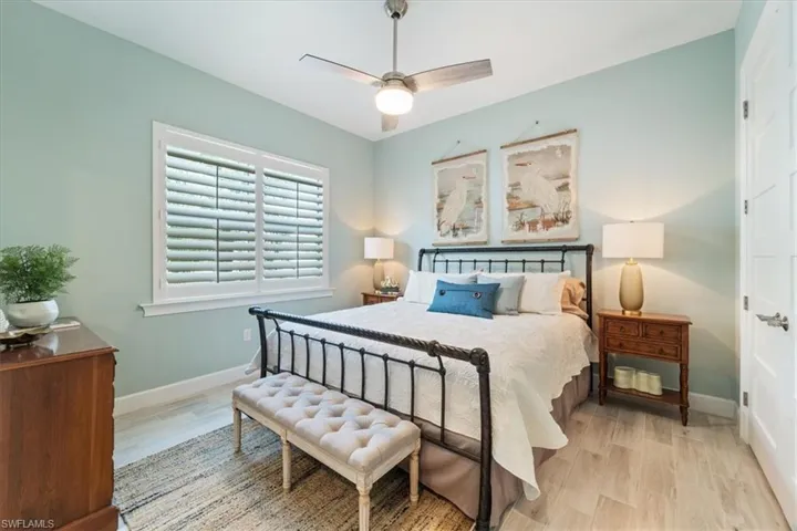 Bedroom with a ceiling fan, light wood-type flooring, and baseboards