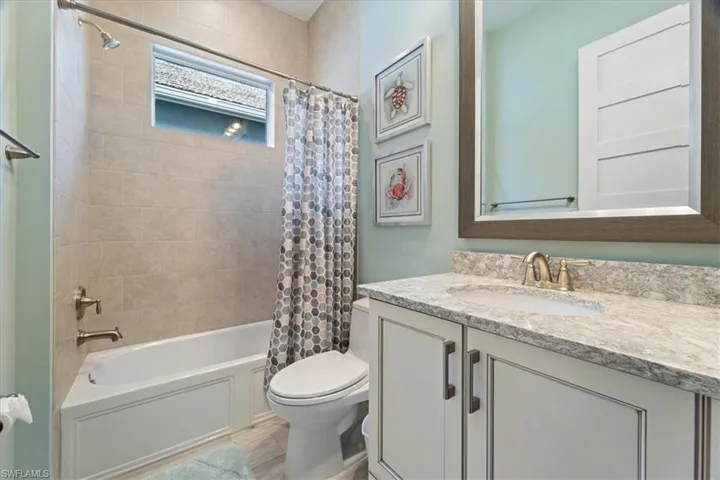 Bathroom featuring vanity, toilet, and shower / bathtub combination with curtain