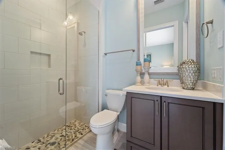 Full bathroom with visible vents, a stall shower, vanity, and toilet