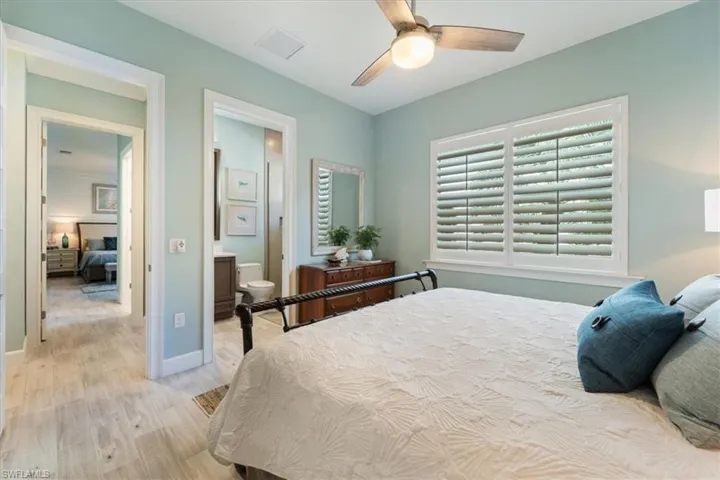 Bedroom featuring visible vents, light wood-style floors, connected bathroom, ceiling fan, and baseboards