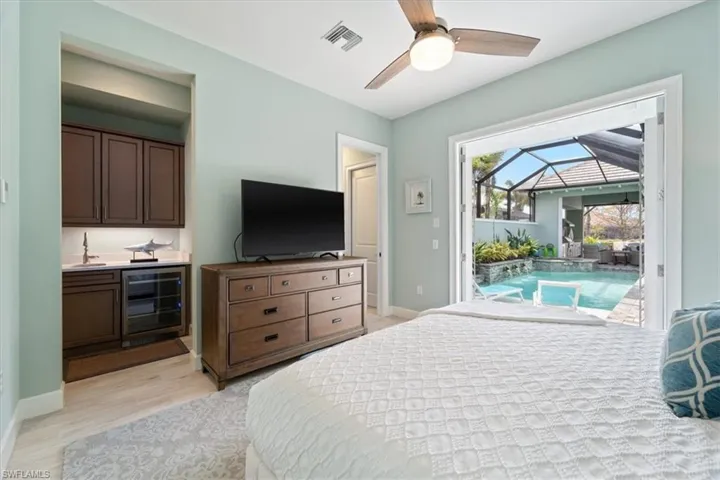 Bedroom with light wood finished floors, beverage cooler, baseboards, a sunroom, and access to outside