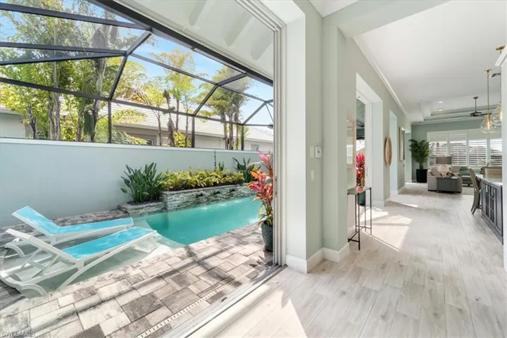 View of pool with glass enclosure, ceiling fan, an outdoor hangout area, and a patio