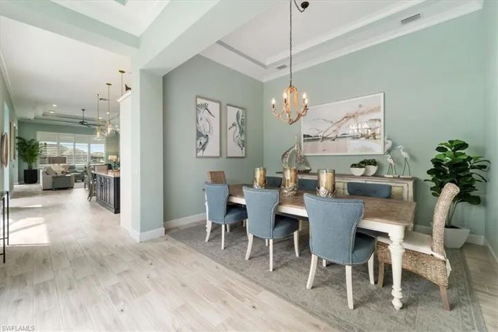 Dining space with a chandelier, a tray ceiling, visible vents, and light wood-style floors