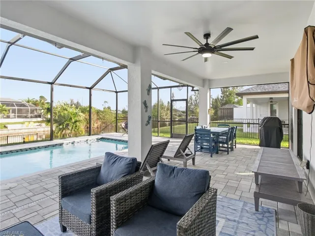 Fenced backyard featuring a lanai, a patio area, a ceiling fan, and a lounging area