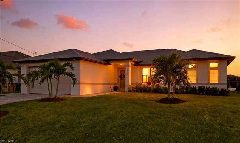 View of front facade with an attached garage, a front lawn, concrete driveway, and stucco siding