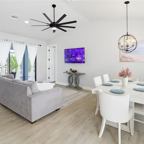 Living room featuring vaulted ceiling, wood finish floors, ceiling fan, recessed lighting, and a chandelier