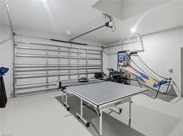 Recreation room featuring finished concrete flooring and a garage