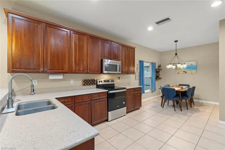 Kitchen with stainless steel appliances, light tile patterned floors, light counters, and wood finish cabinets