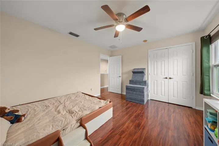 Bedroom featuring wood-style laminate flooring, ceiling fan, and a closet