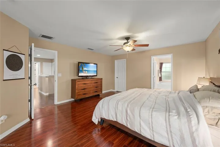 Primary bedroom featuring wood-type flooring, a ceiling fan, and walk-in closet