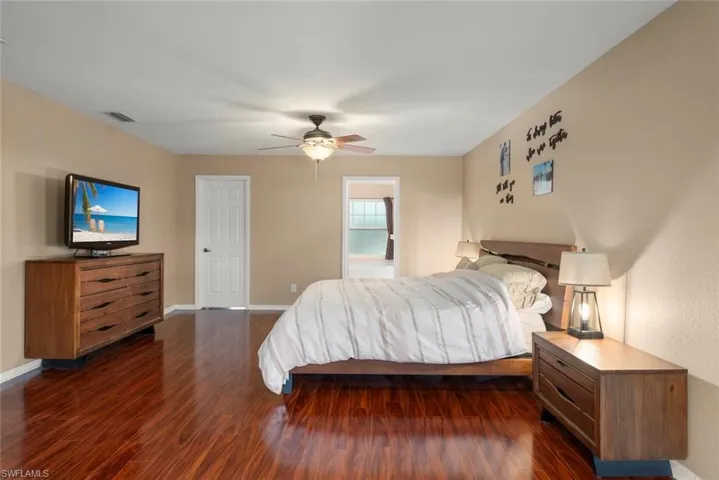 Primary bedroom featuring wood style floors, ceiling fan, and ensuite bathroom