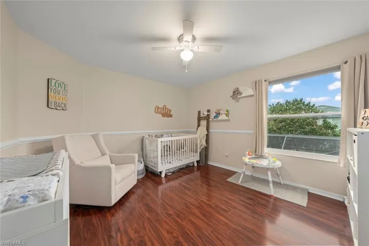 Bedroom with wood-style laminate flooring, ceiling fan, and a window