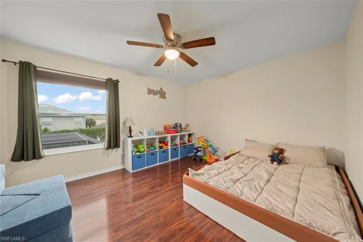 Bedroom with a window, wood-style laminate floors, and a ceiling fan