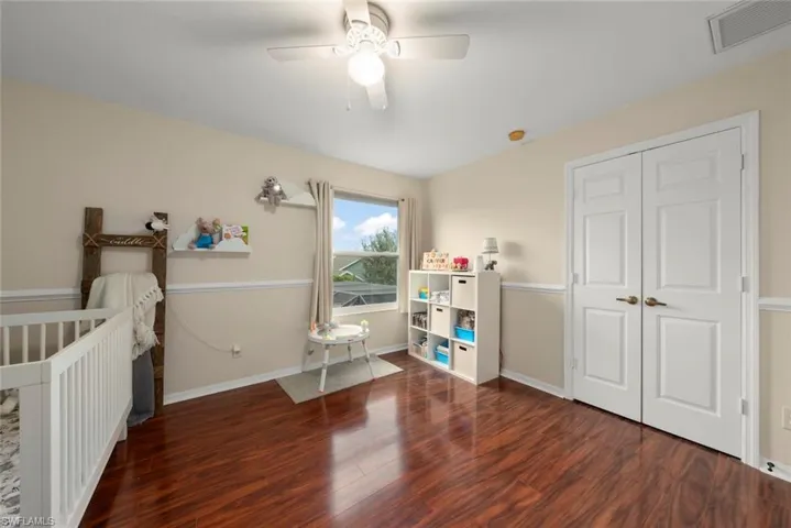 Bedroom with wood-style laminate floors, ceiling fan, and a closet