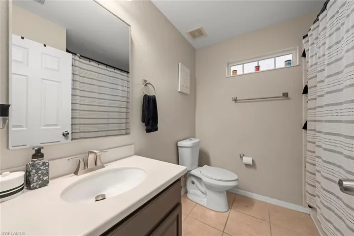 Bathroom with vanity, curtained shower, and tile floors